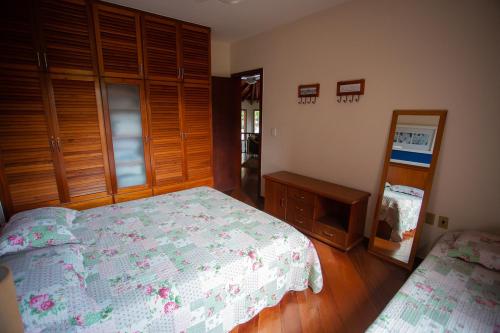 a bedroom with a bed and a dresser and a mirror at Casa a 50m da Praia de Itacoatiara Niteroi RJ in Niterói
