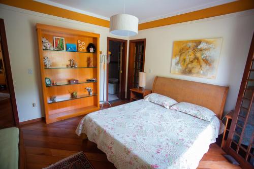 een slaapkamer met een bed en houten vloeren en planken bij Casa a 50m da Praia de Itacoatiara Niteroi RJ in Niterói