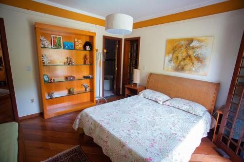 a bedroom with a bed and wooden floors and shelves at Casa a 50m da Praia de Itacoatiara Niteroi RJ in Niterói