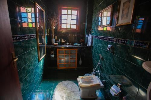 uma casa de banho com paredes em azulejo verde e um lavatório. em Casa a 50m da Praia de Itacoatiara Niteroi RJ em Niterói