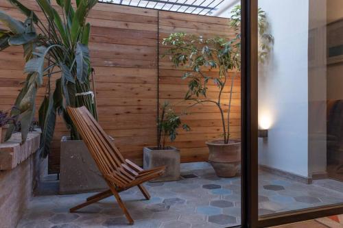 una silla de madera sentada en una habitación con plantas en Brand new - Cozy Apartment- En el corazon de Mendoza en Mendoza