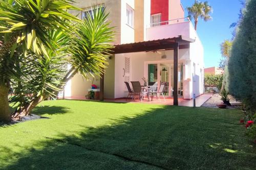 une maison avec une cour avec de l'herbe verte dans l'établissement Tabarca Chalet con jardín y piscina comunitaria, à Peñíscola