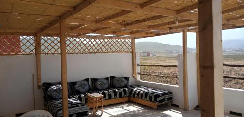eine abgeschirmte Veranda mit einem Sofa und Fenstern in der Unterkunft Repos Surf House 1 in Sidi Ifni