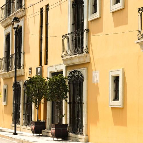 ein gelbes Gebäude mit zwei Bäumen davor in der Unterkunft Quinta Roca Hotel in Oaxaca de Juárez