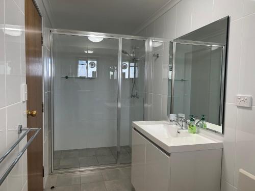 baño blanco con ducha y lavamanos en Glengarry, en Jindabyne