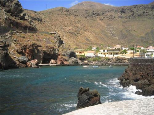 un cuerpo de agua con rocas y casas en una montaña en Apartamentos Boomerang II en Tamaduste