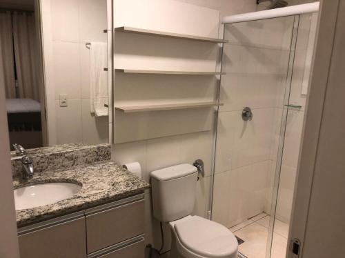 uma casa de banho com um chuveiro, um WC e um lavatório. em Apartamento La Vista em Gramado