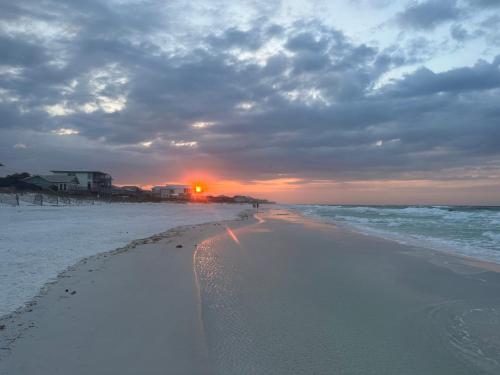 a beach with footprints in the sand and a sunset at Destin-y 30A Beach Retreat Self Checkin - Huge Private Backyard Deck with Outdoor Shower in Santa Rosa Beach