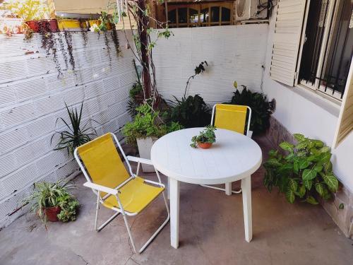 a white table and two yellow chairs on a patio at Portal del sur in San Nicolás de los Arroyos