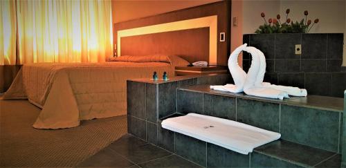 a hotel room with a bed and a bathroom with a swan statue at Hotel Finisterre in Mexico City