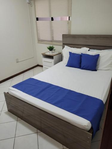 1 dormitorio con 1 cama grande con almohadas azules en Apartamento vista mar com 3 quartos e churrasqueira, en Itapema