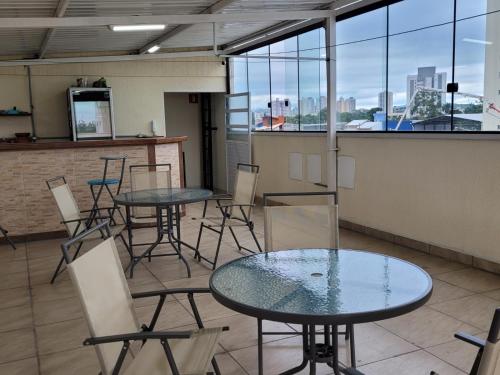 two tables and chairs in a room with windows at Hotel Flamboyant Taubate in Taubaté