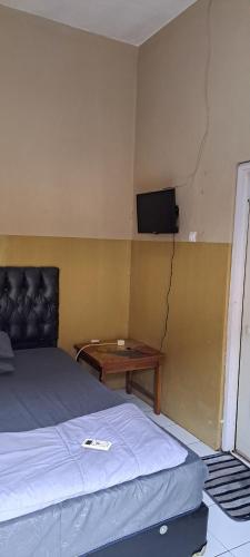 PONDOK CHILLY في تْشيريبون: غرفة نوم مع سرير وتلفزيون على الحائط