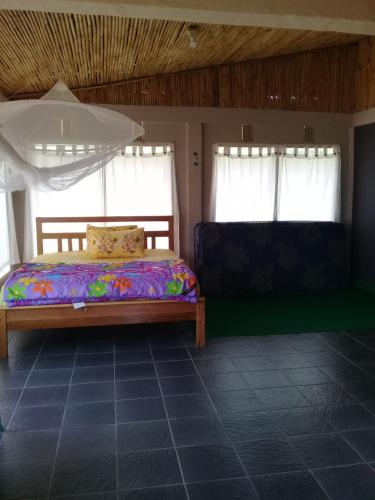 a bedroom with a bed and two windows at Purabarang Homestay in Rantepao