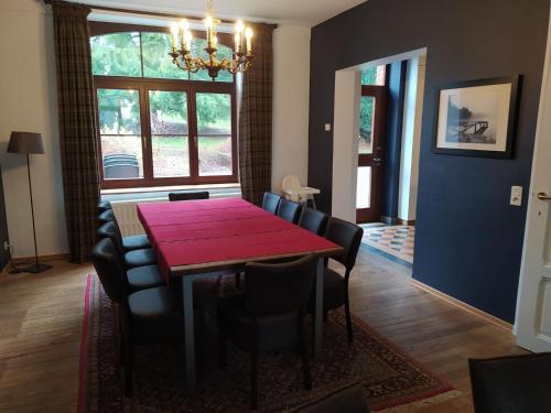 a dining room with a red table and chairs at A beautifully renovated mansion in the Ardennes in Vielsalm