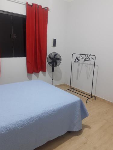 ein Schlafzimmer mit einem weißen Bett und einem roten Vorhang in der Unterkunft Casa grande em arapongas in Arapongas