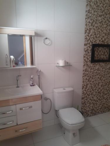 a white bathroom with a toilet and a sink at Casa grande em arapongas in Arapongas