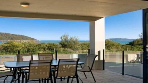 een patio met tafels en stoelen en uitzicht op de oceaan bij Luro 2 - Waterfront Luxury in Ettalong Beach