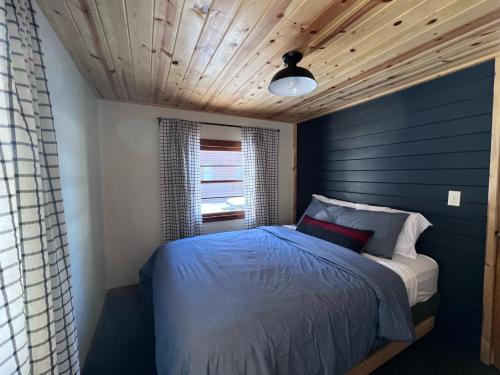 een slaapkamer met een bed met een blauwe muur bij Kona Kona Resort & Cabins in Laporte