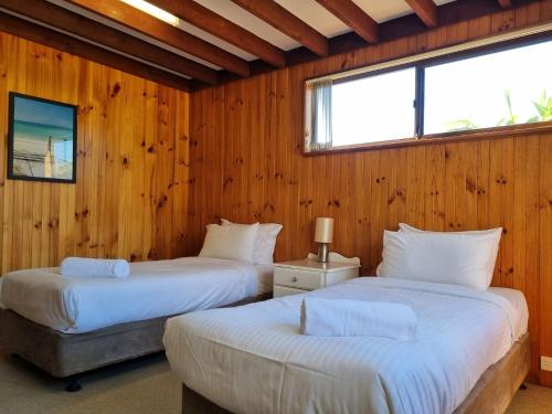 2 Betten in einem Zimmer mit Holzwänden in der Unterkunft Sunbakers in Forster