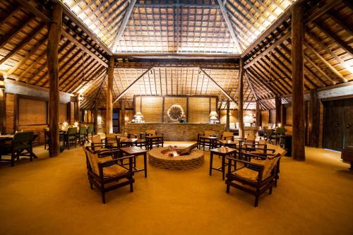 a dining room with tables and chairs in a building at Tiger Tops Karnali Lodge in Bardiyā