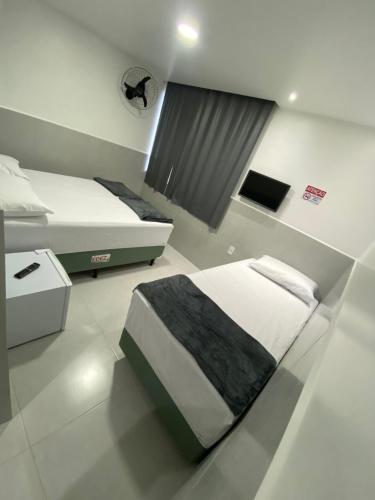 1 Schlafzimmer mit 2 Einzelbetten und einem Fenster in der Unterkunft Suíte com banheiro privativo em Pousada recém construída,a 500mts do pátio do forró in Caruaru