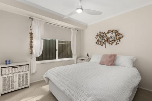 a white bedroom with a bed and a window at Crowford Sands in Sanctuary Point