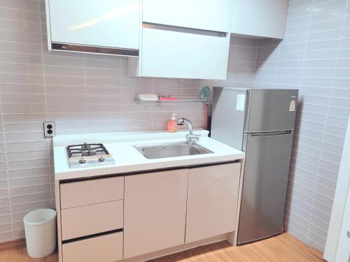 uma pequena cozinha com um lavatório e um frigorífico em Seogwiporto em Seogwipo