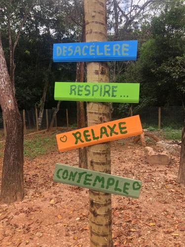 a pole with street signs on a tree at Vila Verde Chalés-Serro in Sêrro
