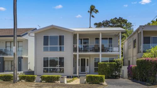 une maison avec un palmier devant dans l'établissement Family Beachhouse - Waterfront Ettalong Beach, à Ettalong Beach