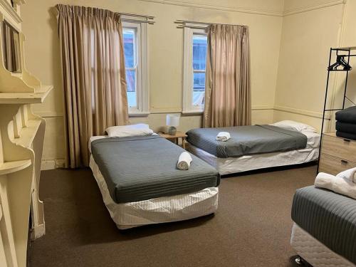 two beds in a room with two windows at Royal Hotel - Accommodation only in Parkes