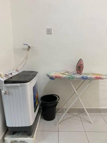 a table in a room with a trash can at Homestay Dafinah with swimming pool in Jitra