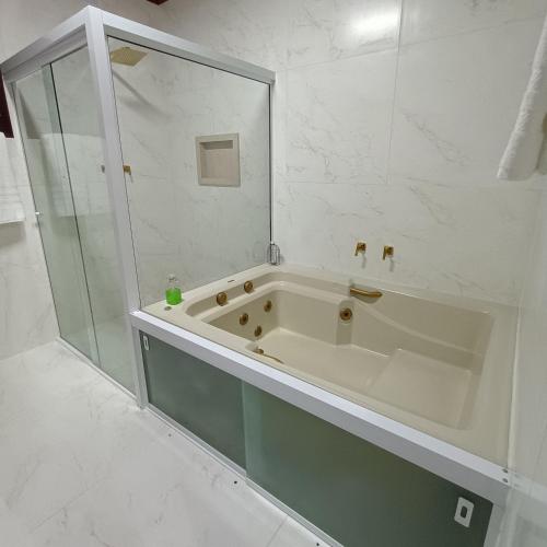 a white bathroom with a tub and a shower at Chalés Alto do Capivari in Campos do Jordão