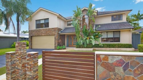 a house with a wooden fence in front of it at Tranquil Lagoon - Waterfront Luxury in Daleys Point