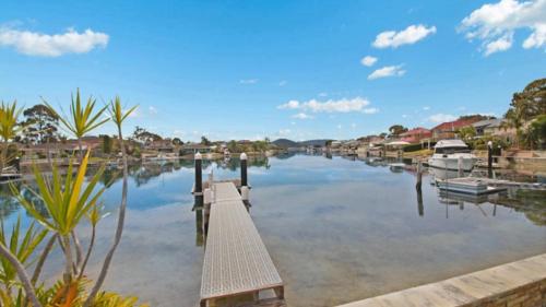 a river with a dock and boats on it at Tranquil Lagoon - Waterfront Luxury in Daleys Point
