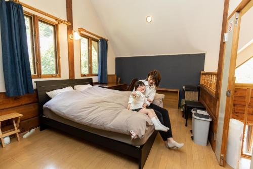 a woman and a child sitting on a bed at Log House Kizuki - Vacation STAY 62486v in Tsuru 