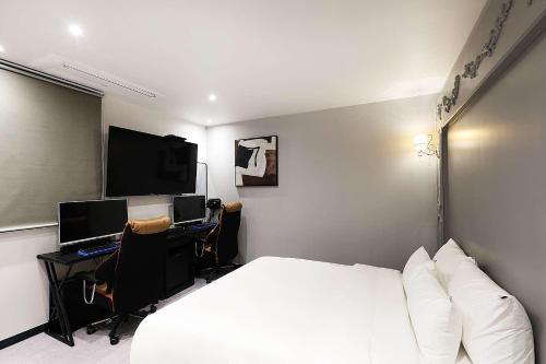 a bedroom with a bed and a desk with a computer at Mariposa Hotel Songtan in Pyeongtaek