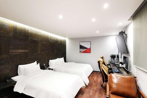a hotel room with two beds and a desk with a computer at Mariposa Hotel Songtan in Pyeongtaek