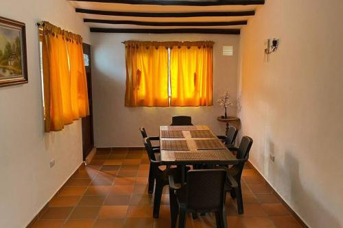 comedor con mesa, sillas y cortinas amarillas en Hermosa casa en Villa de Leyva, en Villa de Leyva