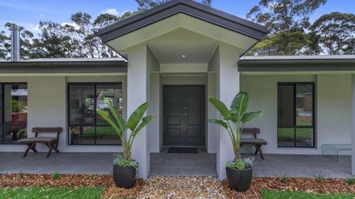 a house with a green door and two plants at Jewellers Retreat - Pearl Beach in Pearl Beach
