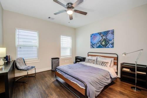een slaapkamer met een bed, een bureau en een plafondventilator bij Cozy Downtown Modern Townhome in Houston