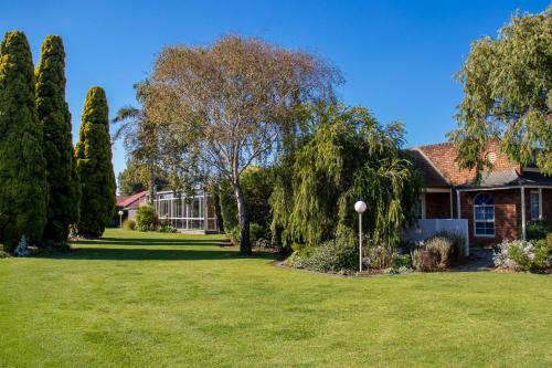 a house with a yard with trees and grass at Arkana Motor Inn & Terrace Apartments in Mount Gambier
