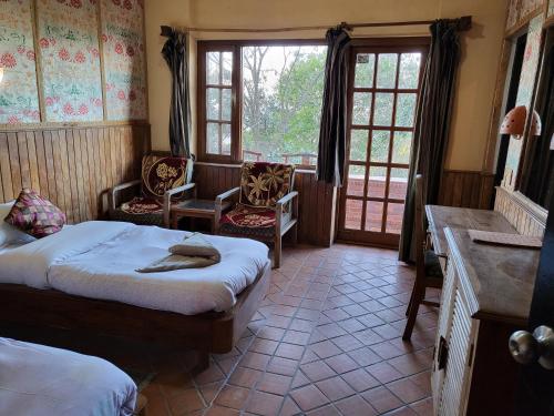 a bedroom with two beds and chairs and windows at NALDUM VILLAGE RESORT By The Edge Nagarkot in Nagarkot