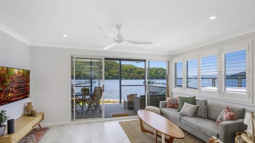 a living room with a couch and a table at Sam's Shack Waterfront Woy Woy Bay in Woy Woy