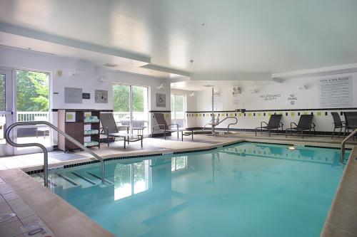 une grande piscine avec des chaises et des tables dans l'établissement Fairfield Inn & Suites by Marriott Millville Vineland, à Millville