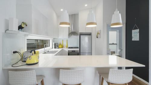 - une cuisine blanche avec un comptoir et des chaises blancs dans l'établissement Beach St Cottage - Ettalong, à Ettalong Beach