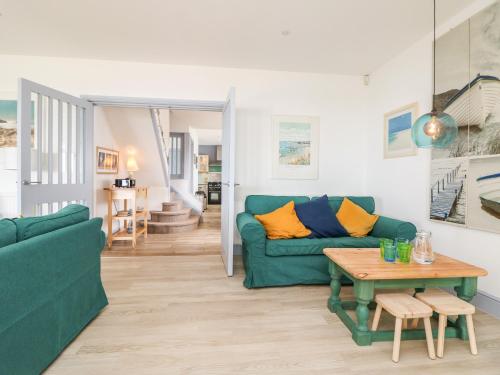 a living room with a green couch and a table at Trelawns in Mawgan Porth