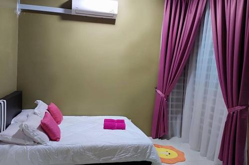 een slaapkamer met een bed met roze kussens en een raam bij CASA Singgah Homestay in Chemor