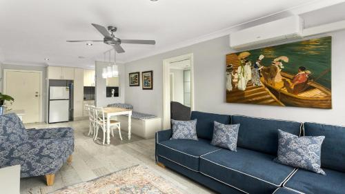 a living room with a blue couch and a painting on the wall at Seas The Dream Ettalong Beach in Ettalong Beach