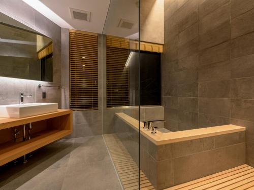 a bathroom with a sink and a shower and a tub at Yukihyo by H2 Life in Niseko